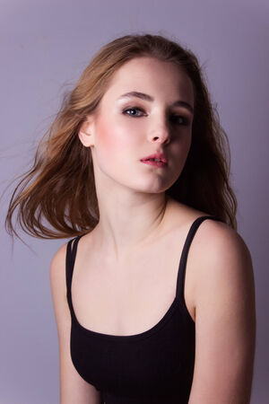 young, beautiful girl in a black t-shirt. Professional model posing in Studio on white-gray background. Take a model test of a young pretty girlの写真素材