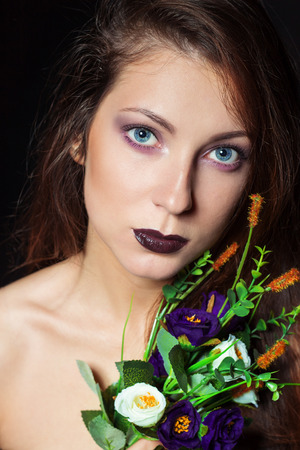 beautiful girl with dark hair and bright make-up with a bouquet of purple flowers in the Studio on a black background. new year\\\\\\\\の写真素材