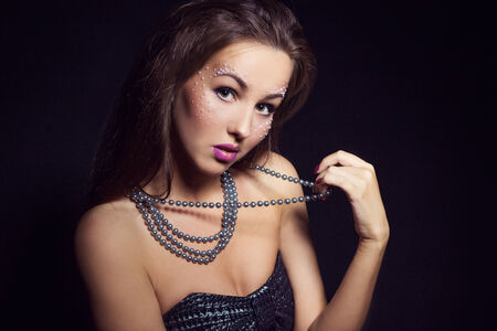 beautiful girl with dark hair and bright makeup with beads in hand in the Studio on a black background. new year\\\\\\\\の写真素材