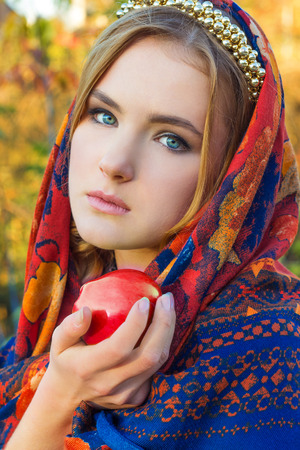 beautiful young sweet girl in a headscarf with the rim on the head with a red Apple in his hand, like a fairy tale character with blue eyesの写真素材