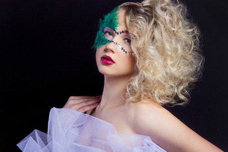 The beautiful young woman in a green mysterious venetian mask a new year carnival, Christmas masquerade, a dance club, secret night party, with beautiful makeupの写真素材