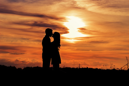 beautiful shade loving happy couple kissing at sunset in a field of warm summer dayの写真素材