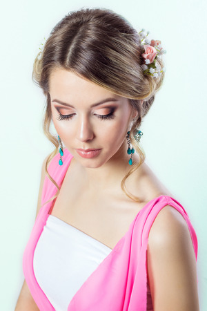 delicate image of a beautiful woman girl like a bride with bright makeup hairstyle with flowers roses in the head in a long pink dressの写真素材