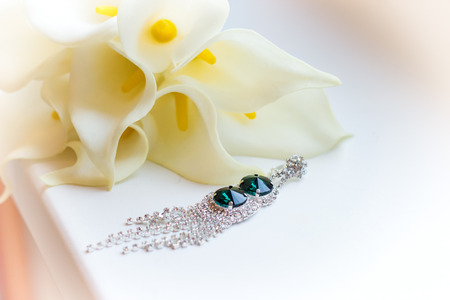 beautiful earrings on the windowsill near white flowers Kala wedding bouquetの写真素材