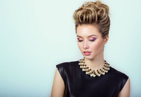 portrait of a beautiful happy sexy young woman smiling in a black evening dress with hair and make-up with expensive jewelry in Studio on white backgroundの写真素材
