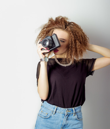 beautiful young sexy woman in jeans with a camera in the hands of curly hair in the Studioの写真素材