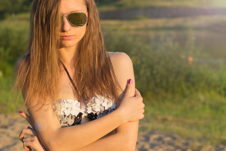 Beautiful sexy girl with long hair with tanned skin wearing sunglasses on the beach of Sunny warm dayの写真素材
