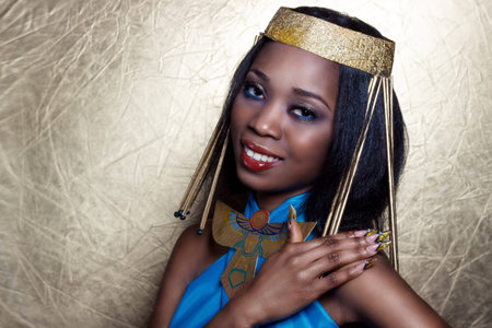 beautiful dark-skinned girl black woman in the image of the Egyptian queen with red lips bright makeup demonstrates long nailsの写真素材