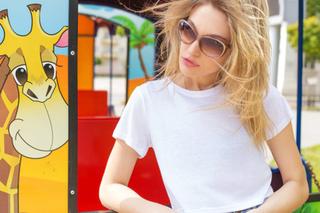 beautiful sexy girl in a white Tshirt and shorts in dzhisovyh amusement park in sunglasses hair develops windの写真素材