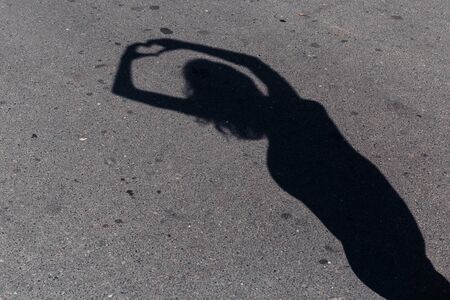 shadow is a beautiful slender girl on the pavement with heart in handsの写真素材