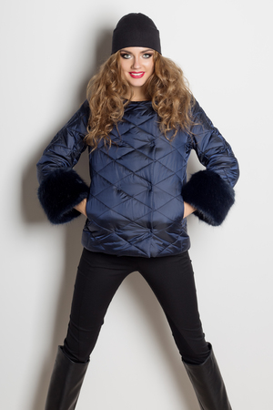 beautiful sexy girl with bright makeup posing in the coat in the studio on a white background, shot for the catalogの写真素材