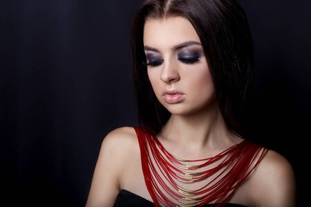 fashion portrait of beautiful young girl with a bright evening make-up for an evening look with beautiful bright jewelryの写真素材