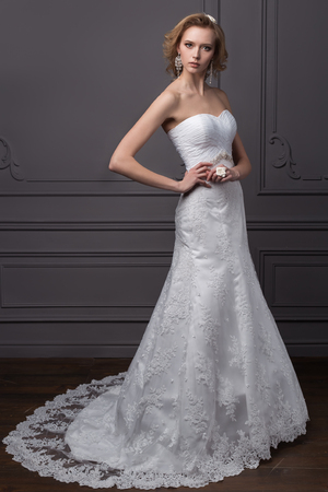 beautiful gentle girl groom in a wedding dress with hairstyle and make-up, hair decorated with a wreath of flowersの写真素材