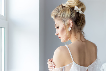 beautiful cute sweet young girl in a light dress beautiful boudoir with bright makeup smokey eyes with a beautiful evening hairstyle and jewelry handmadeの写真素材
