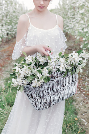 beautiful sweet gentle happy girl in a beige boudoir dress with flowers in a basket holding, photo processing in the style of modern fine artの写真素材