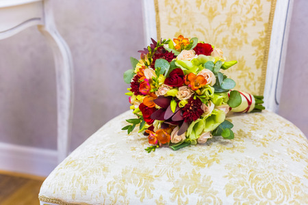 beautiful bouquet of colorful flowers and green roses lying on a chair close-upの写真素材