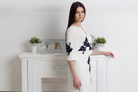 beautiful elegant woman with long hair with a gentle make-up in the studio shows elegant white business dressの写真素材