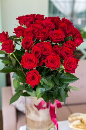 beautiful big bouquet of roses in a vase standing on the tableの写真素材