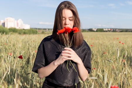beautiful cute sexy young woman with full lips with short hair in a field with poppy flowers in their handsの写真素材