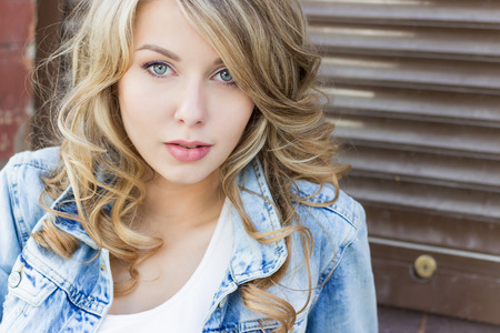 beautiful funny blonde girl with big lips with a charming smile, wearing jeans and a white shirt walking in the city solnetsnym summer dayの写真素材