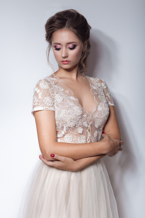 beautiful cute sweet girl with a beautiful bride with bright makeup evening wedding hairstyles in modern trendy wedding dress in the studioの写真素材