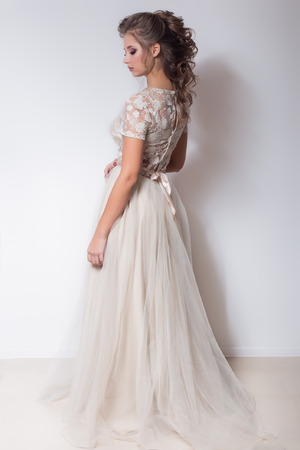 beautiful cute sweet girl with a beautiful bride with bright makeup evening wedding hairstyles in modern trendy wedding dress in the studioの写真素材
