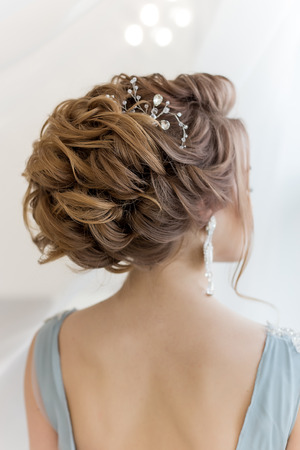 Beautiful volume hairstyle for a bride in a gentle blue dress with large earrings and adornment in hairの写真素材