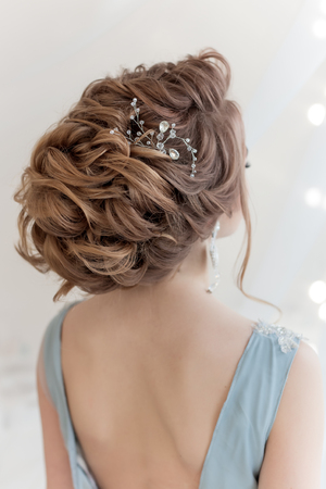 Beautiful volume hairstyle for a bride in a gentle blue dress with large earrings and adornment in hairの写真素材