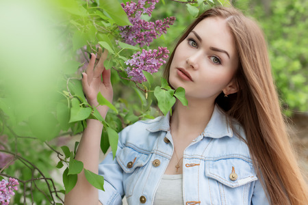 Beautiful young girl with red hair in the garden with lilacの写真素材