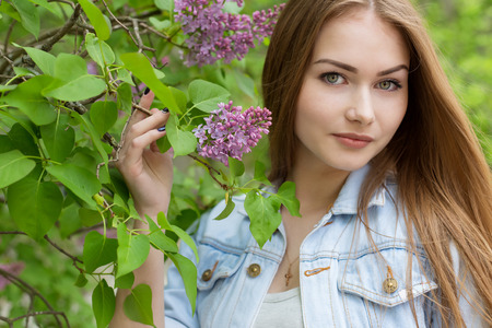 Beautiful young girl with red hair in the garden with lilacの写真素材