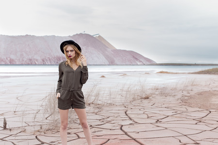 Beautiful sexy slender girl in a black hat in the mountains with a strong windの写真素材