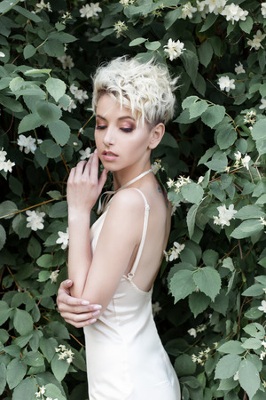 Beautiful sexy tender girl with short haircut in cream dress with jasmine flowerの写真素材
