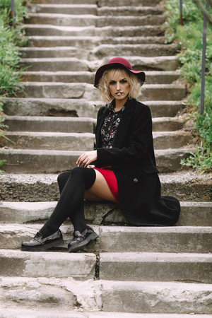 Beautiful cute girl in red hat and black coat walking in the cityの写真素材