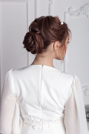 beautiful young tender girl bride in white dress with a wreath on head with blue eyes with a wedding hairstyle in a beautiful white dress with train in studioの写真素材