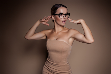 beautiful business woman in a business dress and glasses on a brown background in the studioの写真素材