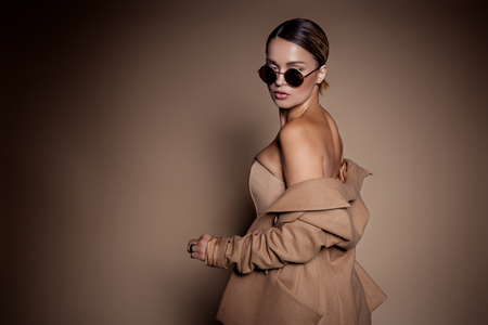beautiful business woman in a business dress and glasses on a brown background in the studioの写真素材