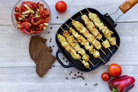chicken skewers in a pan with pepper salad and tomato and spicesの写真素材