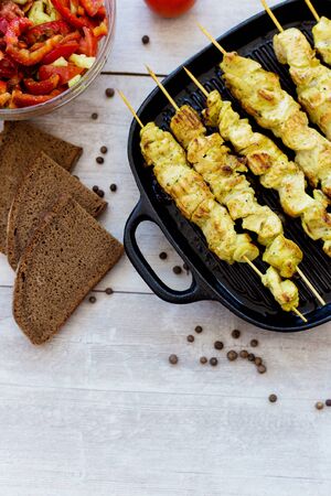 chicken skewers in a pan with pepper salad and tomato and spicesの写真素材