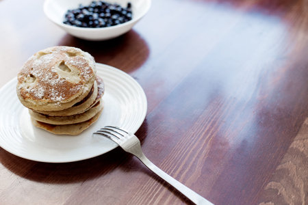 pancakes with berries and powdered sugar in a white plate are on the tableの写真素材