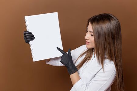 girl medical worker in black gloves in a white suit with a magazine in her handsの写真素材