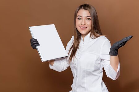 girl medical worker in black gloves in a white suit with a magazine in her handsの写真素材