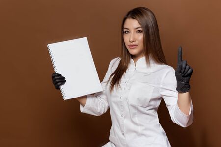 girl medical worker in black gloves in a white suit with a magazine in her handsの写真素材