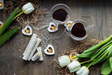 two cups of coffee on valentine's day with sweets and tulip flowersの写真素材