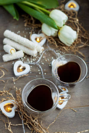 two cups of coffee on valentine's day with sweets and tulip flowersの写真素材