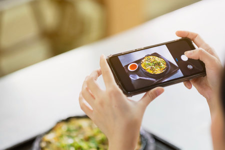A girl take a picture of some food by smartphone in restaurant