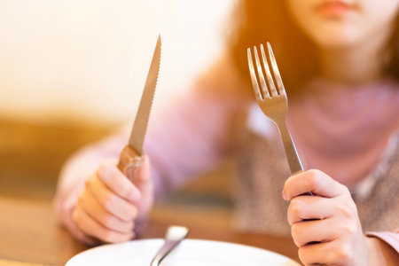 A woman with Steak knife and empty white dish in Steak house,A hungry women waiting for some foodの写真素材
