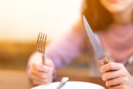 A woman with Steak knife and empty white dish in Steak house,A hungry women waiting for some food
