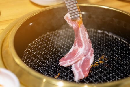 Woman grilling pork in a Korean restaurantの写真素材