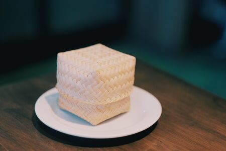 Bamboo box and sticky rice on white dish in Thai restaurantの写真素材