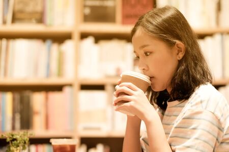 Asian girl drinking hot coffee on paper coffee cupの写真素材